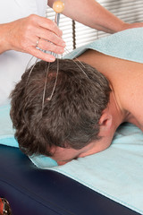 Female therapist doing head massage on man