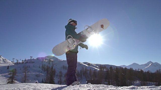 SLOW MOTION: Snowboarder girl spinning a snowboard