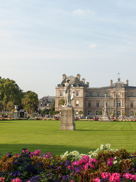 People enjoy sunny day in the Luxembourg Garden in Paris. Luxembourg Palace is the official residence of  the French Senate.