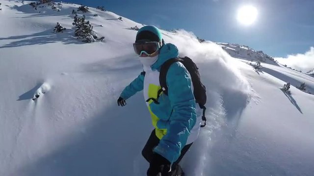 SELFIE: Snowboarder riding powder on a sunny mountain in winter