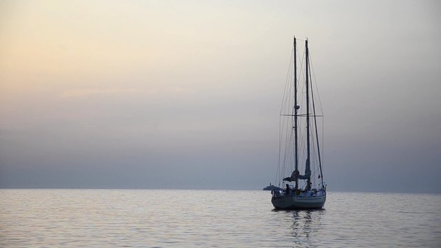 Sail boat with reflection sets up sails 