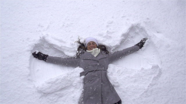 SLOW MOTION: Young woman making snow angels