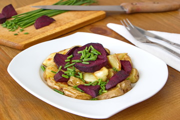 pieces of beetroot served with baked potatoes and chive on the wooden table