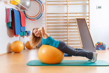 Young woman doing gymnastic exercises on a gym ball.
