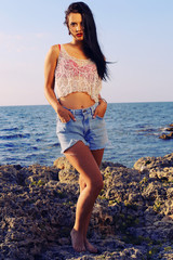 sexy beautiful woman wears a top with jeans shorts and posing beach