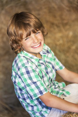 Happy Boy Child Sitting Smiling on Hay Bales