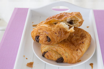 croissants with chocolate filling on a white plate on a white tray. breakfast. French pastries. side and top view, high key.
