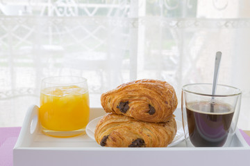 croissants with chocolate filling on a white plate, orange juice, coffee. French pastries. side and top view, high key.
