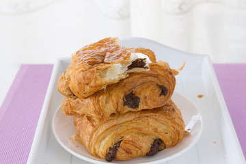 croissants with chocolate filling on a white plate on a white tray. breakfast. French pastries. side and top view, high key.