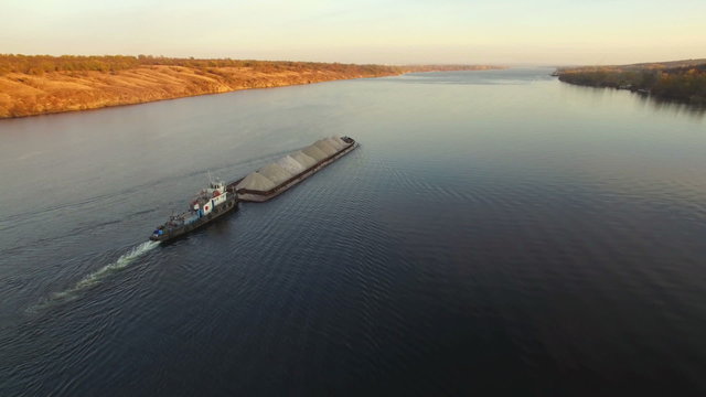 Aerial view of tug boat pushing barge of sand