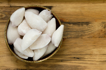 frozen squids in dish on brown wooden background