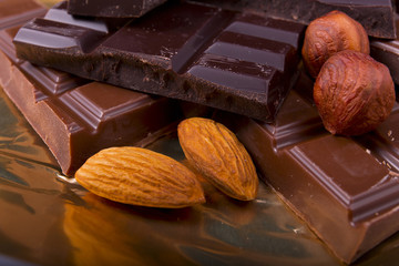 black and milk chocolate with nuts on a foil background