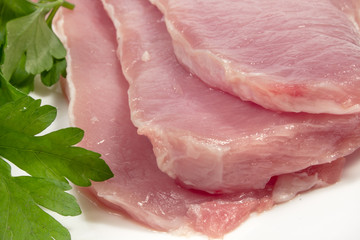 Close-up of raw pork meat, beside fresh parsley