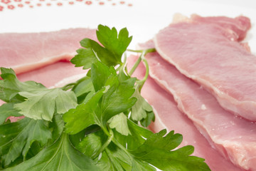 Raw pork loins and leaves of fresh parsley