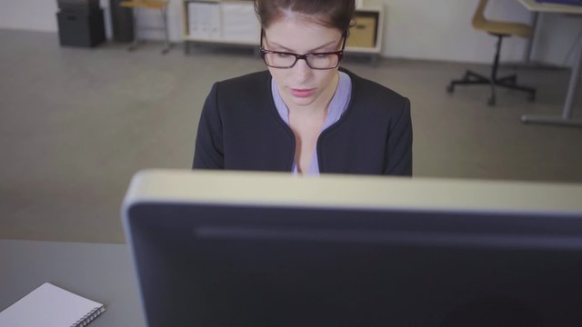 junge mitarbeiterin im b&uuml;ro sitzt am computer