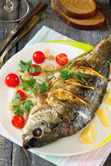 Baked fish with lemon on a dark wooden style