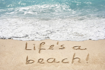 Concept or conceptual hand made or handwritten text in sand on a beach