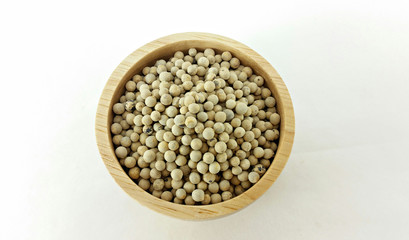 white pepper in wooden bowl on white background