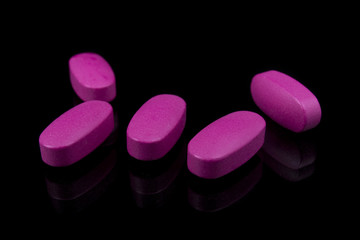 pink pills vitamins on a black background