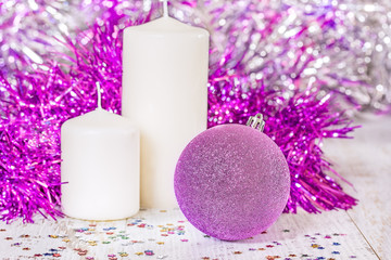 Obraz na płótnie Canvas Lilac Christmas ball and two white candles
