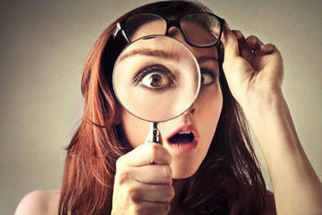Shocked woman looking through a magnifying glass