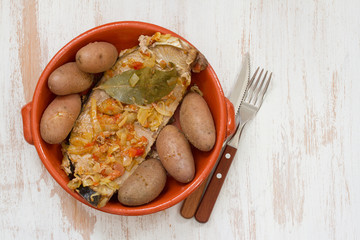 tuna with onion and potato in ceramic dish on white wooden background