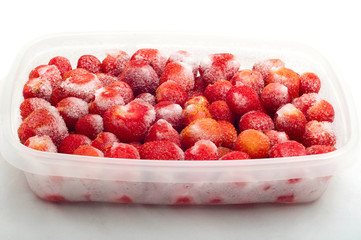 frozen strawberries in plastic box isolated on white