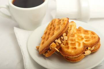 cup of morning coffee and fresh waffles in the shape of heart on