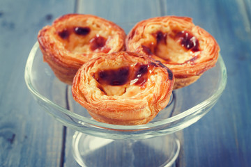 traditional portuguese cookies pasteis de nata on white dish on blue wooden background