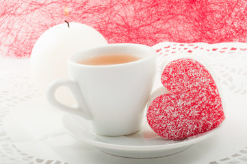 heart-shaped cake with a cup of green tea and  grief white candl