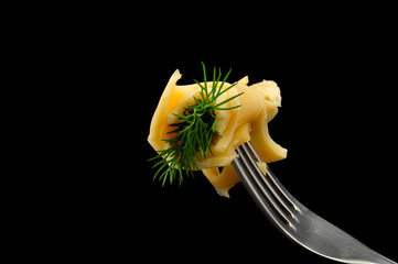 cheese and dill on a fork on black background