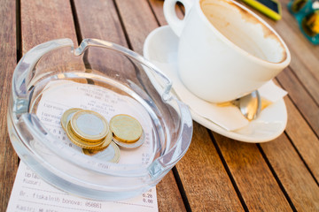 coffee with few coins and bill on wood table