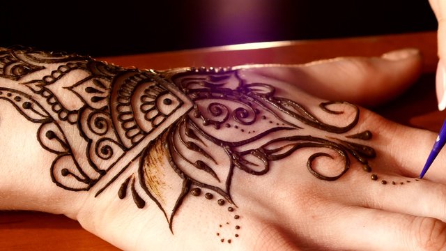 Womans hand decorated with mehendi, on black background