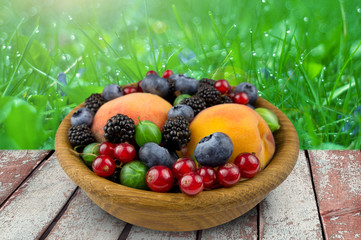 fruits and berries in a wooden plate, gooseberry, blackberry, pe