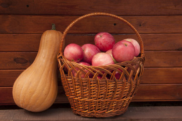basket with apples and pumpkin in wooden wall