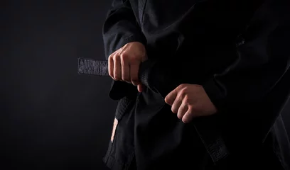 Papier Peint photo Lavable Arts martiaux Gros plan du combattant de karaté masculin attachant le nœud à sa ceinture noire