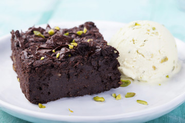 Chocolate brownie, cake, white plate on a turquoise wooden background