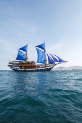Fototapeta na wymiar Vintage Wooden Ship with Blue Sails