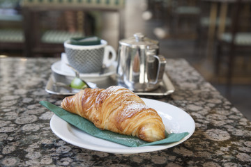 Crossant and Pot of Tea on Cafe Table