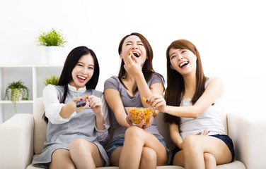 happy young woman group  eating snacks and watching the tv