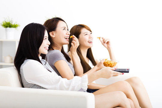 happy young woman group eating snacks and watching the tv