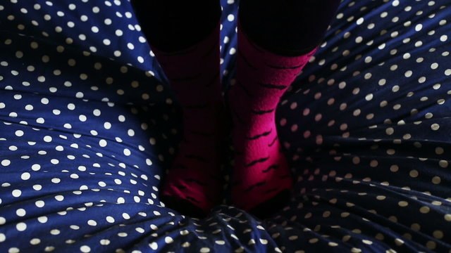 two feets with cool socks that jumping and having fun on bed