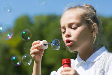 Cute little girl blowing soap bubbles
