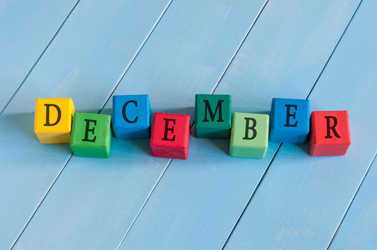 Word December On child's toy cubes on wooden rural  background.