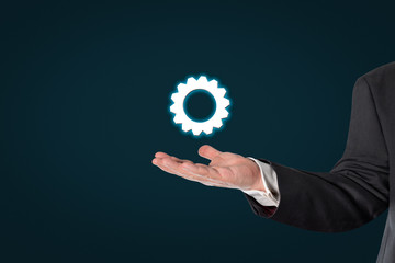 Businessman holding a virtual gear wheel symbol