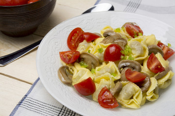 Homemade tortellini stuffed with mushrooms and spring onion and cherry tomatoes