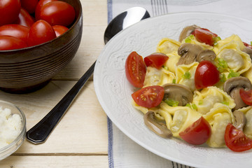 Homemade tortellini stuffed with mushrooms and spring onion and cherry tomatoes