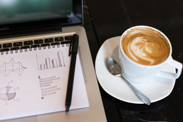 Workplace, laptop and notepad with hand drawn business graph sel