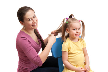 mother is combing a little girl, isolated on white background