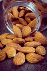 Vintage photo, Almonds spilling out of glass jar on concrete structure